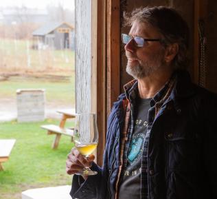 Grey and Gold Cidery owner holding a glass of cider