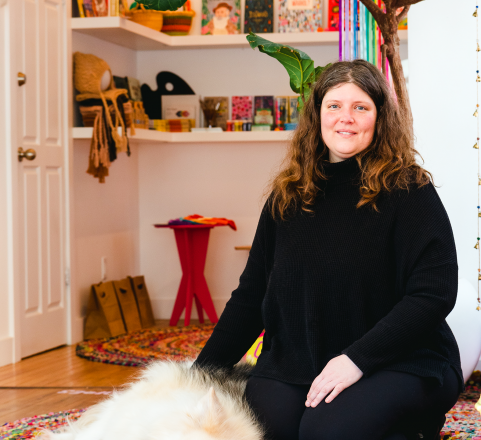 Ashley Green with her dog in front of a bookshelf